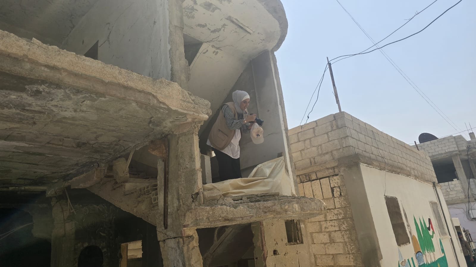 وسوعة المخيمات توثّق أحوال اللاجئين الفلسطينيين في محافظة درعا: عدسة لين محمد، تظهر في الصورة آثار الدمار من الثورة السورية